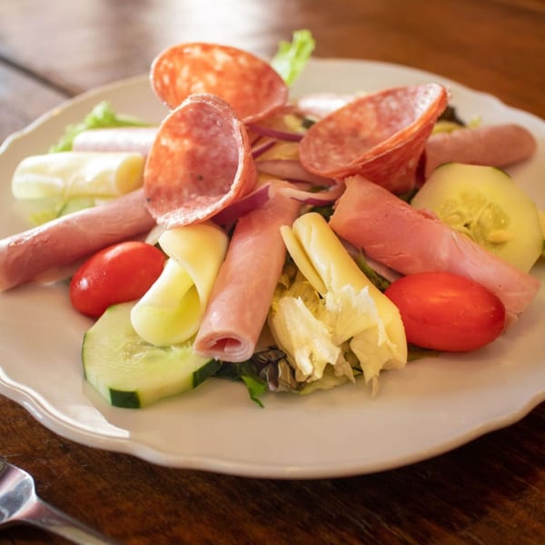 A fresh antipasto salad from Danny's Pizzeria, featuring salami, ham, cheese, tomatoes, and cucumbers.