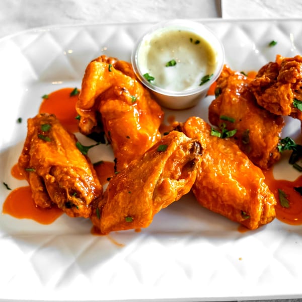Buffalo wings with ranch dressing and parsley on a white plate at Danny's Pizzeria.