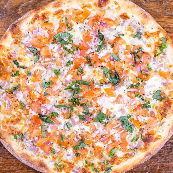 Danny's Pizzeria's white pizza topped with diced tomatoes, red onions, and fresh basil.