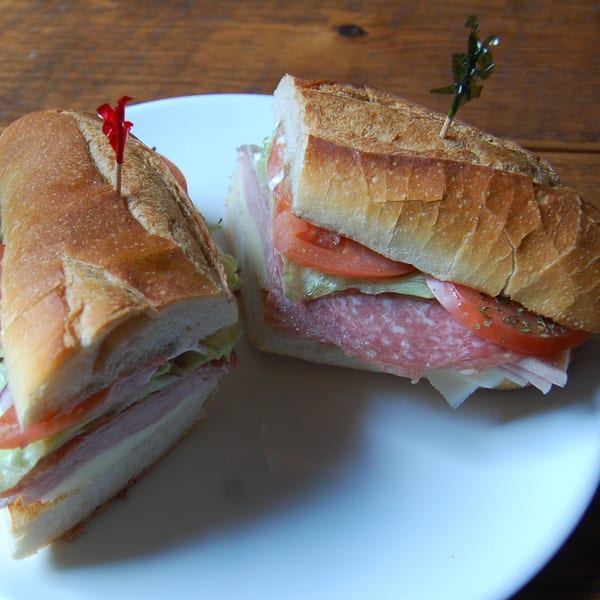 Two halves of a Danny's Pizzeria Italian sub sandwich with deli meats, cheese, and vegetables.